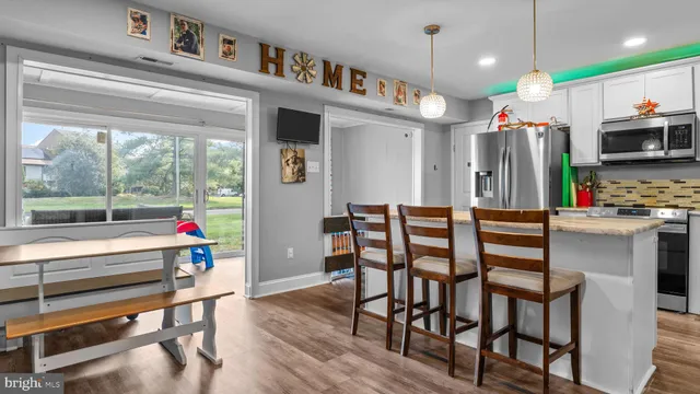 a kitchen with stainless steel appliances kitchen island granite countertop a table chairs sink and cabinets