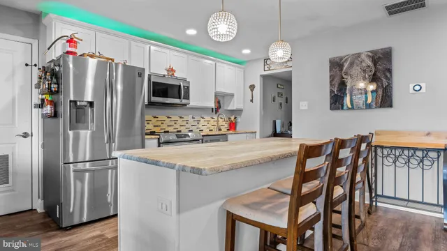 a kitchen with stainless steel appliances granite countertop a refrigerator a microwave oven a sink and a refrigerator