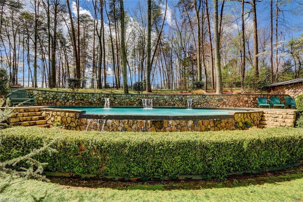 5809 Henson Farm Road Summerfield, NC 27358 - Photo 3 of 29 The backyard oasis is privately nestled in the bank of rear hillside. Fountains adorn this infinity pool, decorative stone walls, rear sundeck and pool house (not shown) for a quick change!