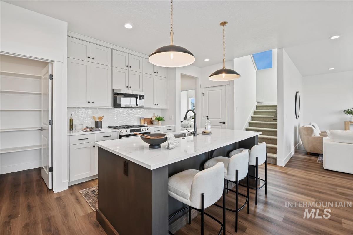 749 South Calhoun Lane Star, ID 83669 - Photo 12 of 34 Kitchen with a kitchen island with sink, two tone cabinetry, light stone counters, a kitchen breakfast bar, and stainless steel appliances
