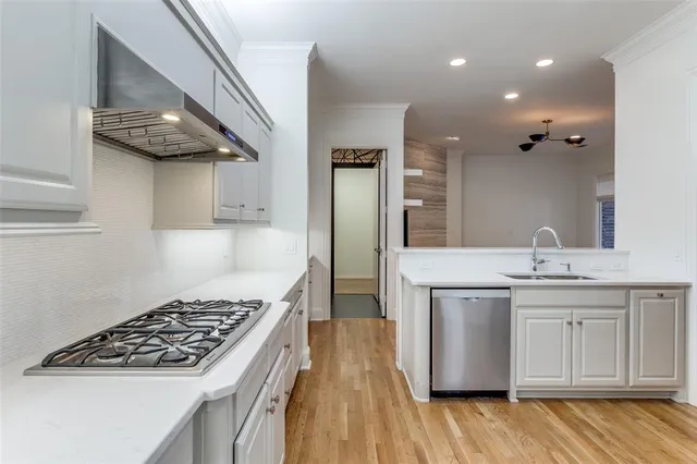 a kitchen with white cabinets a sink and dishwasher with wooden floor