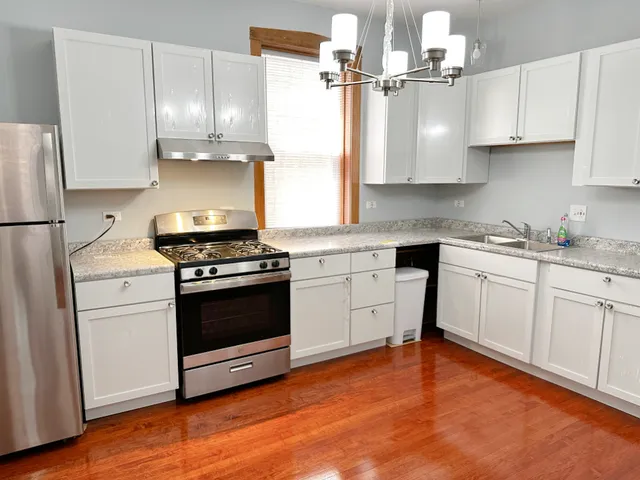 a kitchen with stainless steel appliances a stove a sink and white cabinets