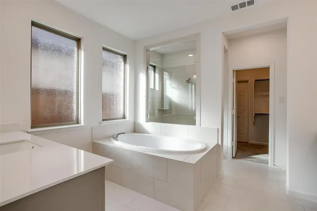 a white bath tub sitting in a bathroom near mirror