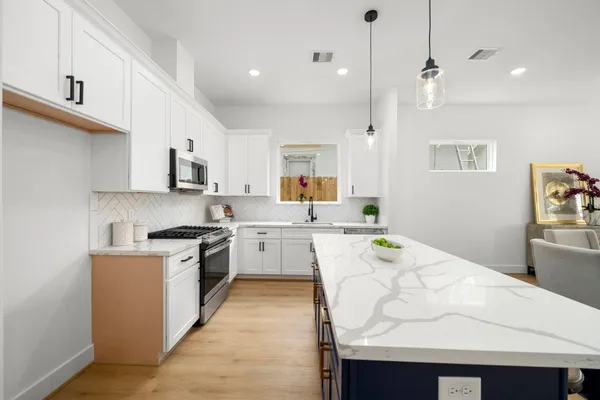 a large kitchen with stainless steel appliances granite countertop a stove a sink and a refrigerator