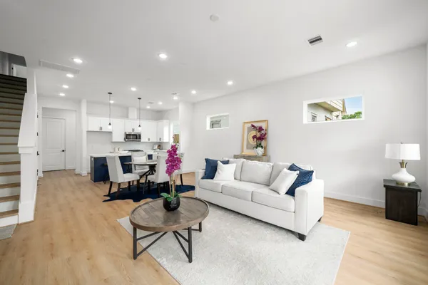 a living room with furniture and kitchen view with wooden floor