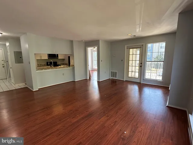 a view of an empty room with a window and wooden floor