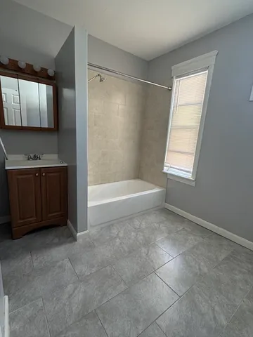 a bathroom with a tub sink vanity and mirror