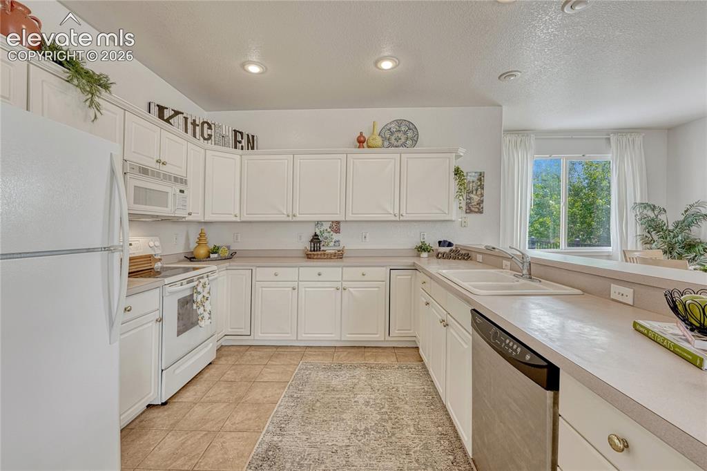 7285 Julynn Road Colorado Springs, CO 80919 - Photo 11 of 45 a kitchen with granite countertop white cabinets and white appliances