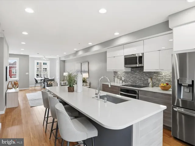 a kitchen with stainless steel appliances granite countertop a sink a stove a refrigerator cabinets and chairs