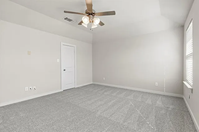 an empty room with a window and a fan