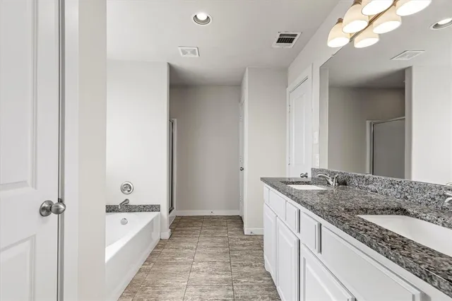 a spacious bathroom with a granite countertop sink mirror and a bath tub