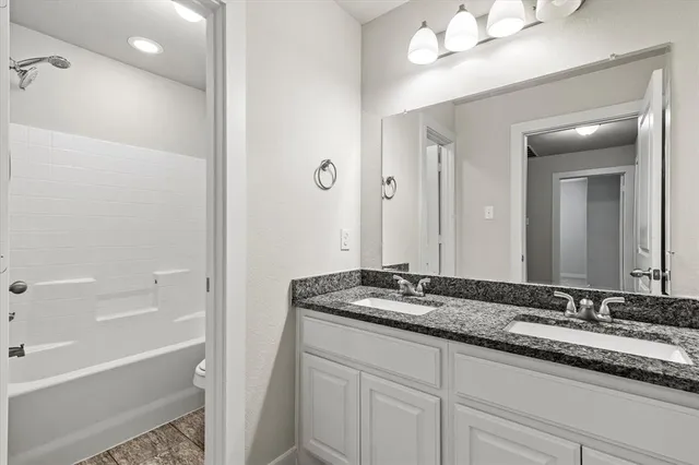 a bathroom with a granite countertop sink mirror and a bathtub