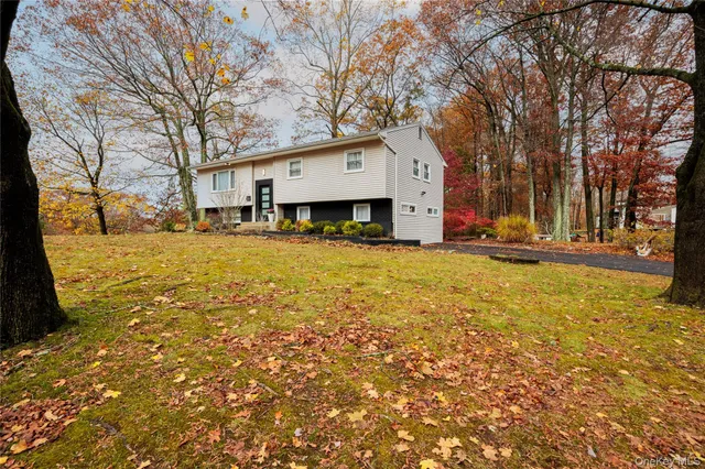 a front view of house with yard and trees in the background
