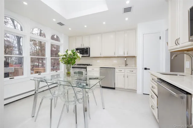 a kitchen with stainless steel appliances white cabinets and wooden floor