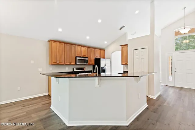 a kitchen with stainless steel appliances a stove a sink a microwave a refrigerator and cabinets