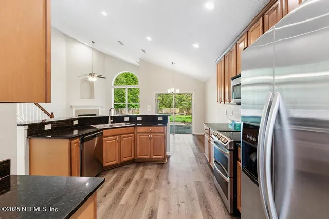 a kitchen with stainless steel appliances kitchen island granite countertop a stove top oven a sink a counter space and cabinets