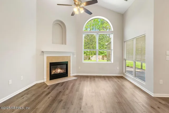 an empty room with wooden floor fan and windows