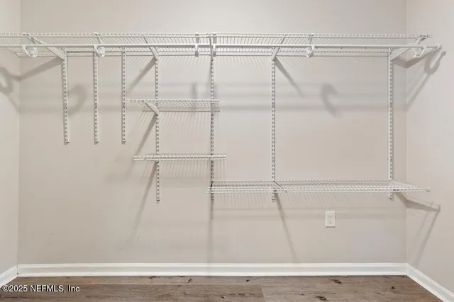 an empty room with wooden floor chandelier fan and windows