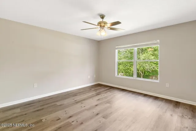 an empty room with wooden floor and a ceiling fan