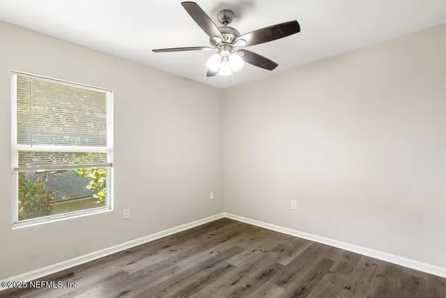 an empty room with wooden floor closet and windows