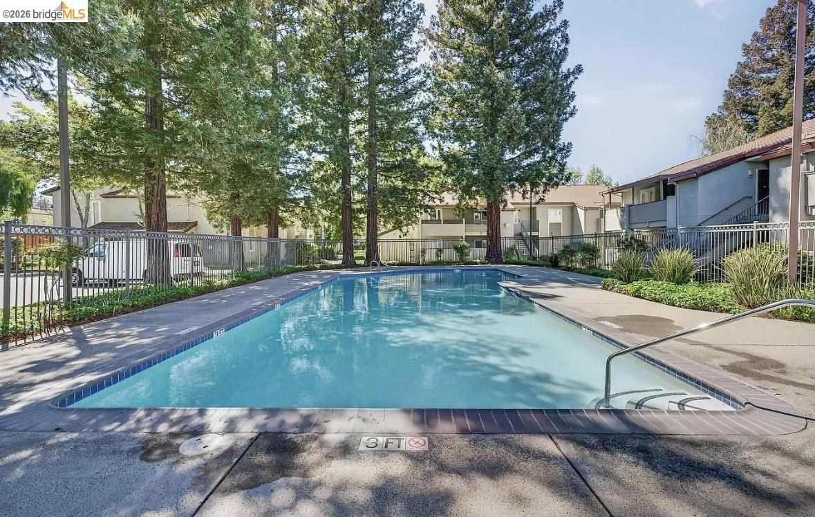 1505 Kirker Pass Road, Unit 214 Concord, CA 94521 - Photo 49 of 55 Rectangular swimming pool with integrated steps, surrounded by concrete decking and metal fencing