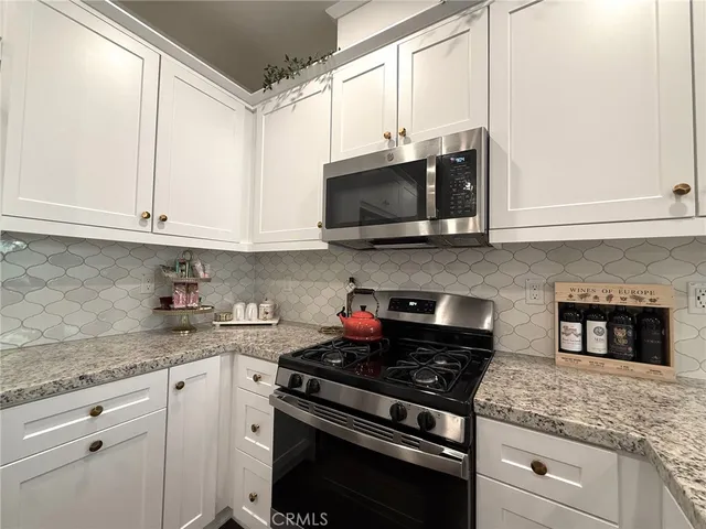 a kitchen with stainless steel appliances granite countertop white cabinets and a stove top oven