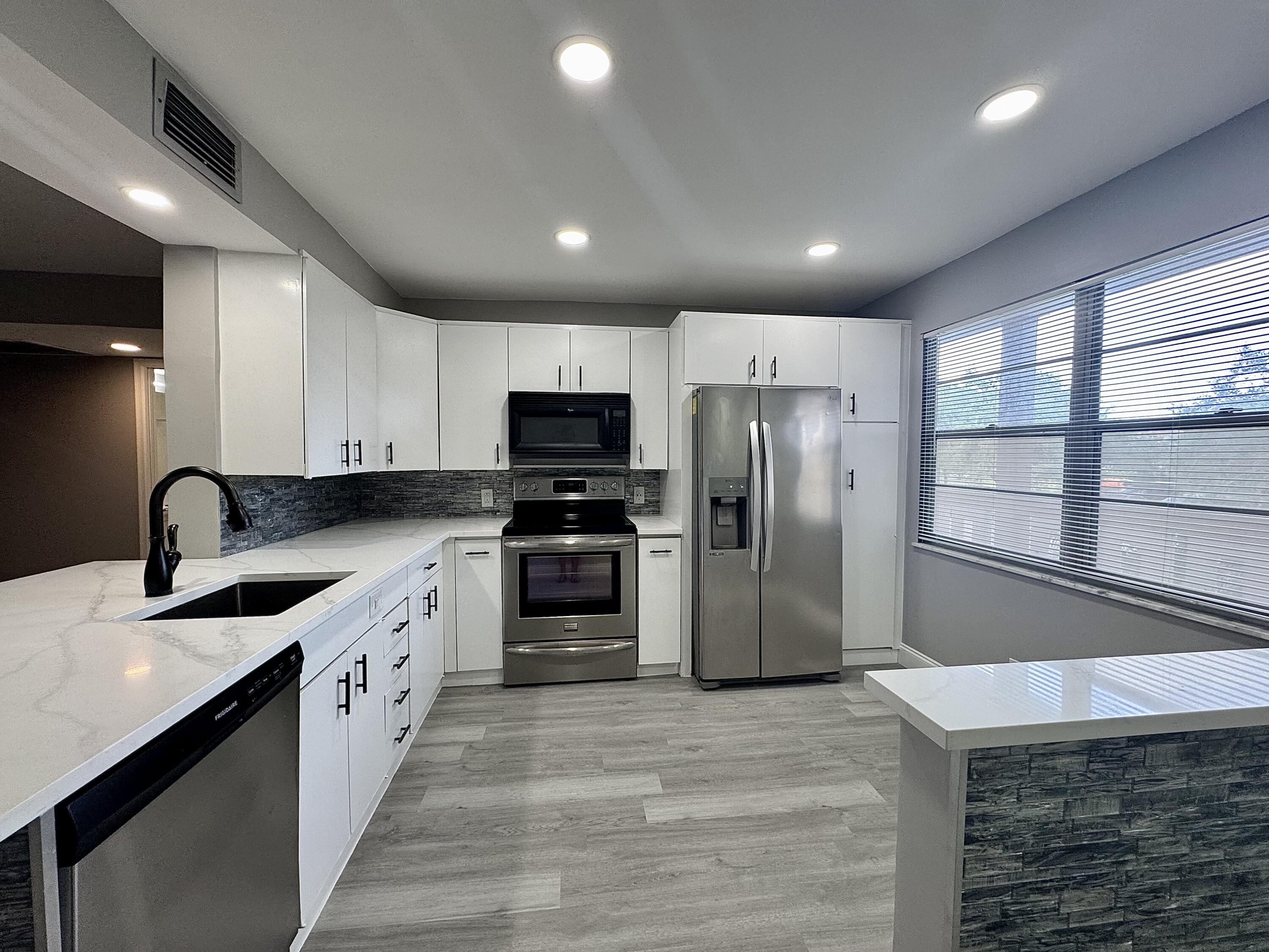 a kitchen with stainless steel appliances granite countertop a refrigerator and a sink