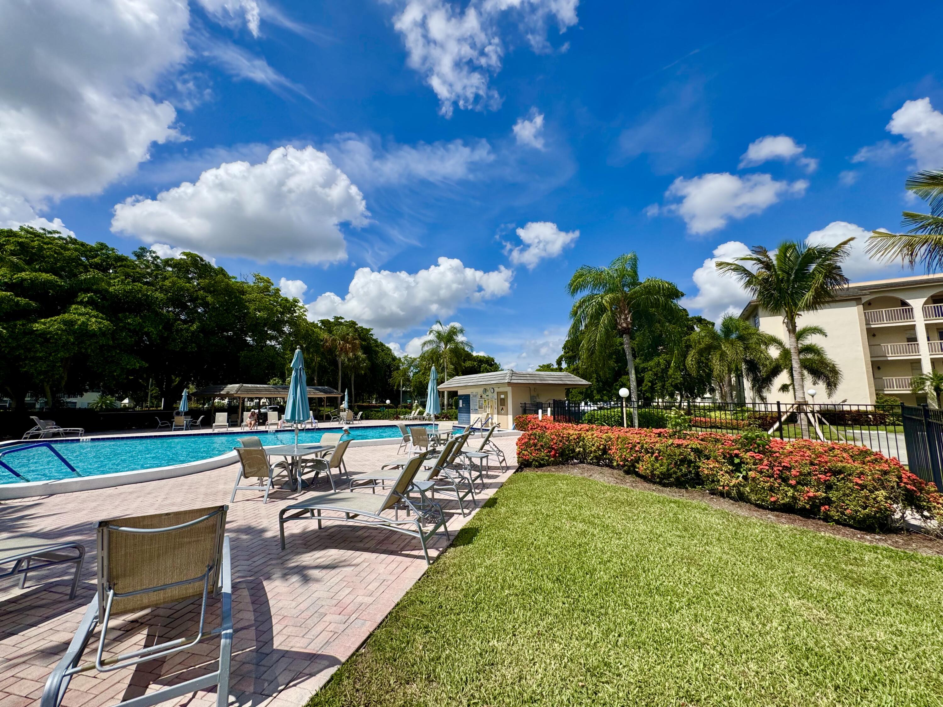4401 Martinique Court, Unit G2 Coconut Creek, FL 33066 - Photo 13 of 22 a view of a swimming pool with lawn chairs and a big yard