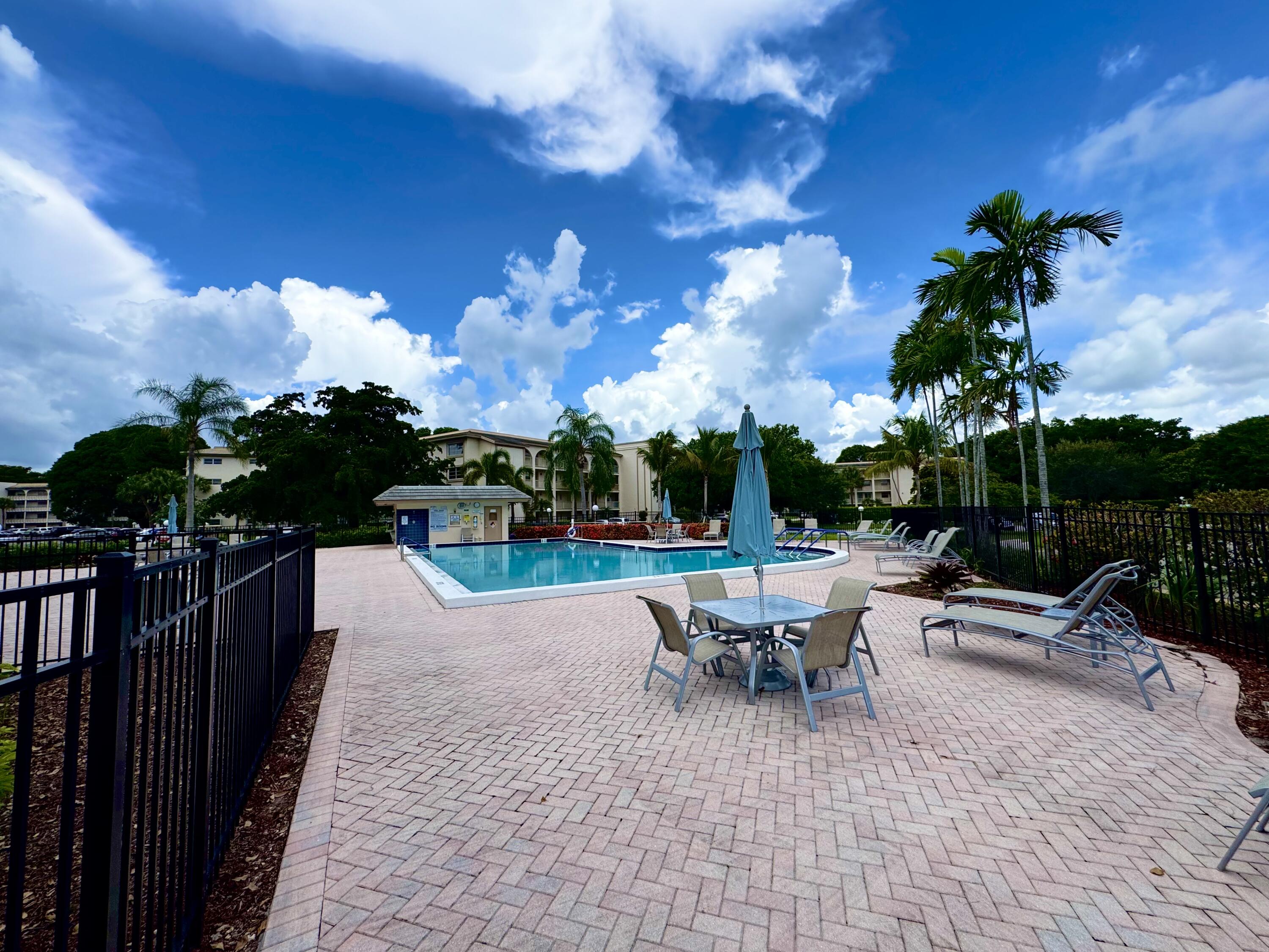 4401 Martinique Court, Unit G2 Coconut Creek, FL 33066 - Photo 14 of 22 a view of a patio with a table and chairs under an umbrella
