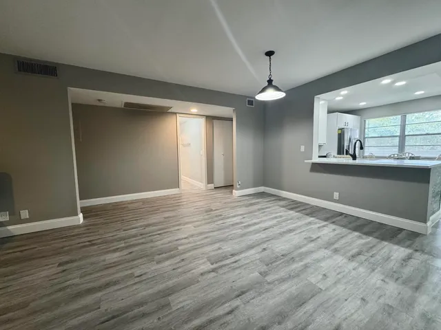 a view of an empty room with window and wooden floor