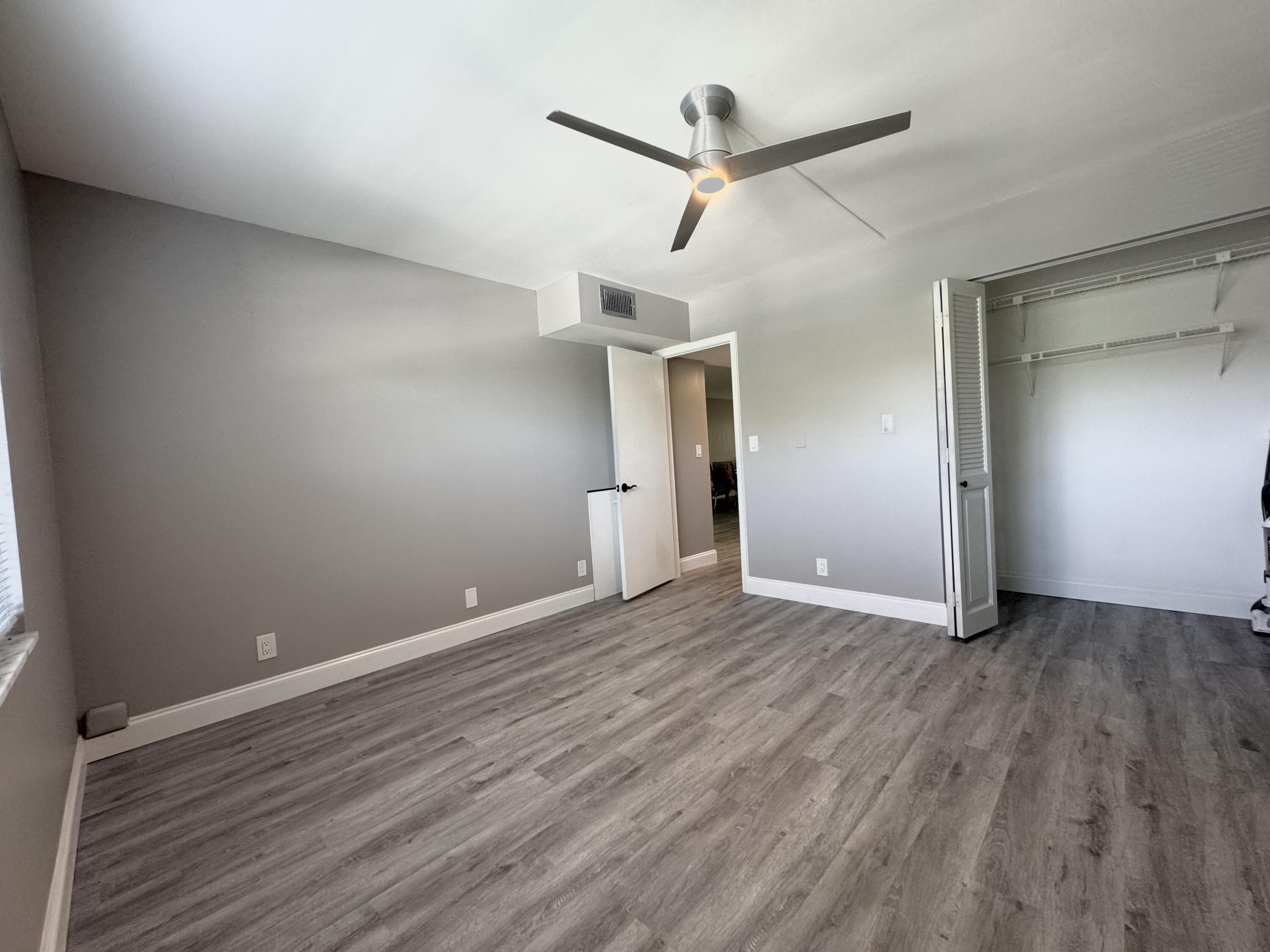 4401 Martinique Court, Unit G2 Coconut Creek, FL 33066 - Photo 8 of 22 an empty room with wooden floor a ceiling fan and windows