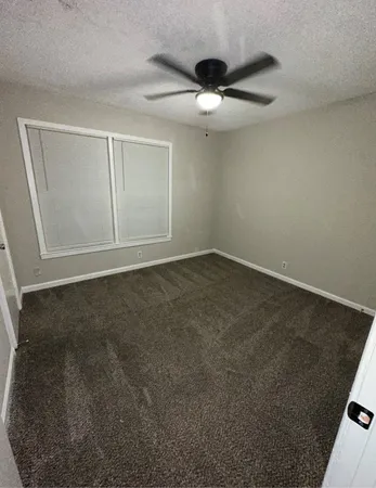 an empty room with a ceiling fan and window