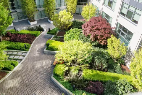 a front view of a building with a garden and trees
