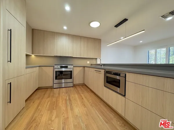 a kitchen with kitchen island a stove a sink and a refrigerator with wooden floor