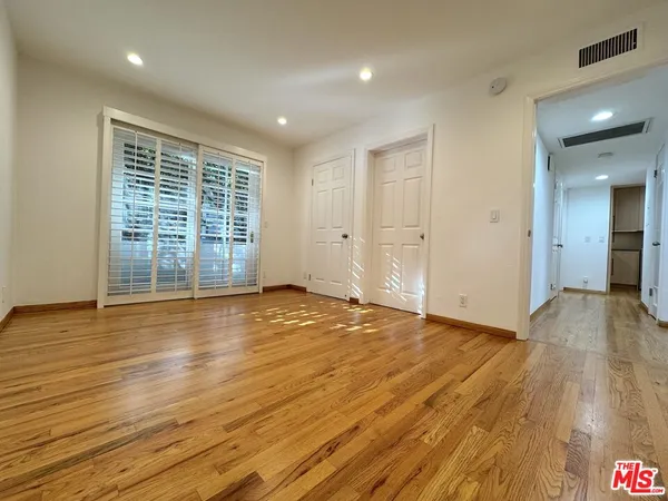 a view of empty room with wooden floor and fan