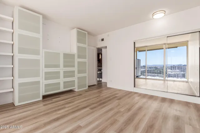 a view of an empty room with a window and wooden floor