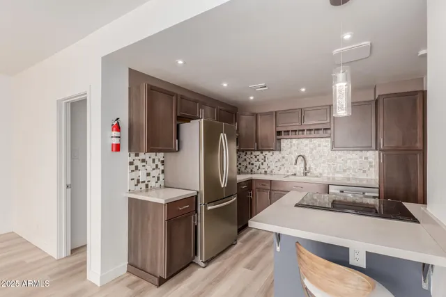 a kitchen with stainless steel appliances kitchen island granite countertop a refrigerator and a stove top oven