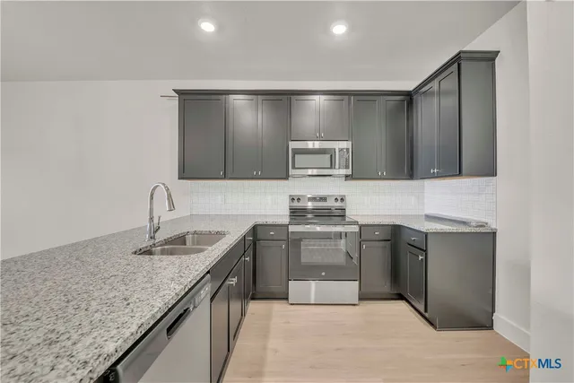 a kitchen with granite countertop stainless steel appliances and wooden cabinets