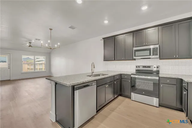 an empty room with wooden floor chandelier fan and windows