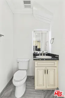 a bathroom with a granite countertop toilet a sink and a mirror
