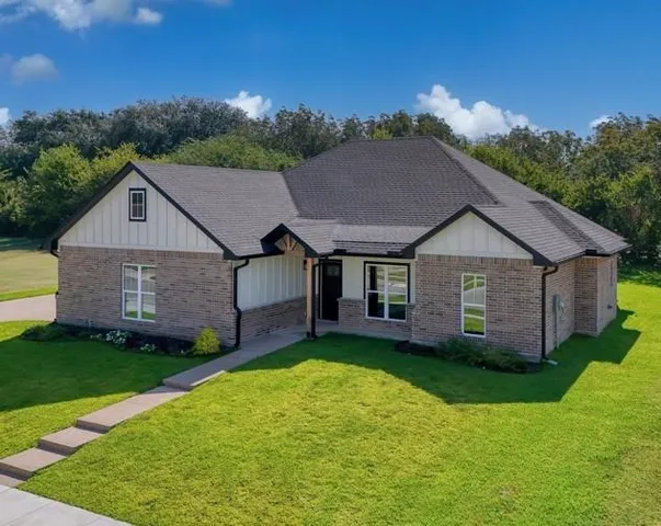 a aerial view of a house with a yard plants and large tree
