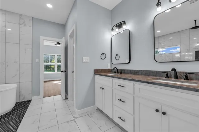 a spacious bathroom with a granite countertop sink a toilet a mirror and shower