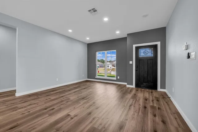 a view of an empty room with wooden floor and window