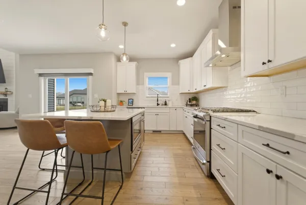 a kitchen with stainless steel appliances a refrigerator a sink dishwasher stove and white cabinets next to a window