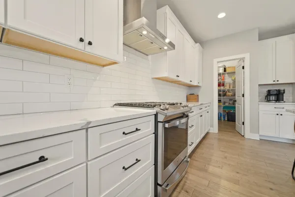 a kitchen with stainless steel appliances a sink dishwasher a stove and white cabinets