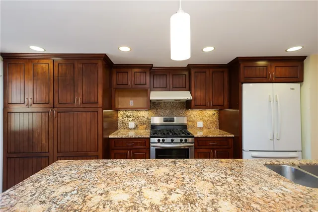 a kitchen with stainless steel appliances granite countertop a refrigerator and a stove top oven