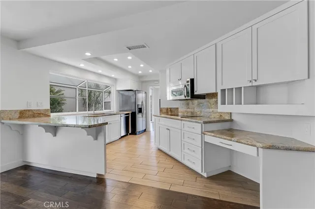 a kitchen with stainless steel appliances granite countertop a stove top oven a sink a counter space and cabinets