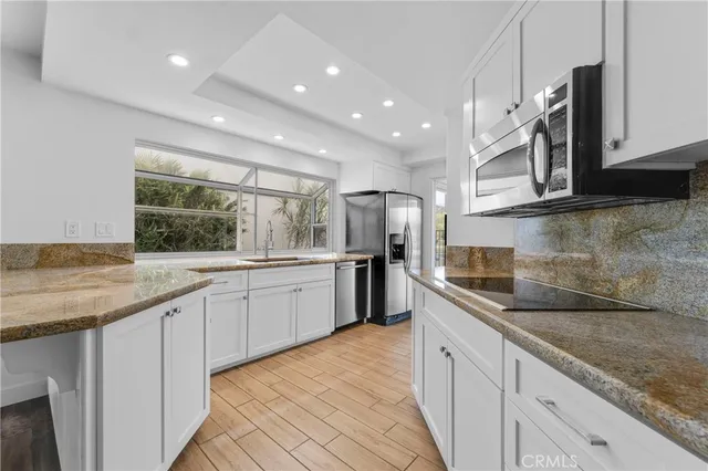 a large kitchen with granite countertop a sink and white cabinets