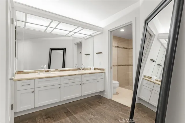 a spacious bathroom with a double vanity sink a toilet and a shower