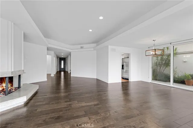 a view of an empty room with wooden floor and a fireplace